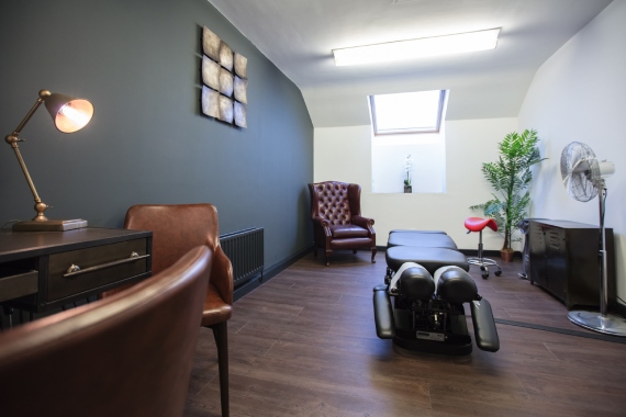 A room featuring a chair, a desk, and a ceiling fan, creating a functional workspace atmosphere